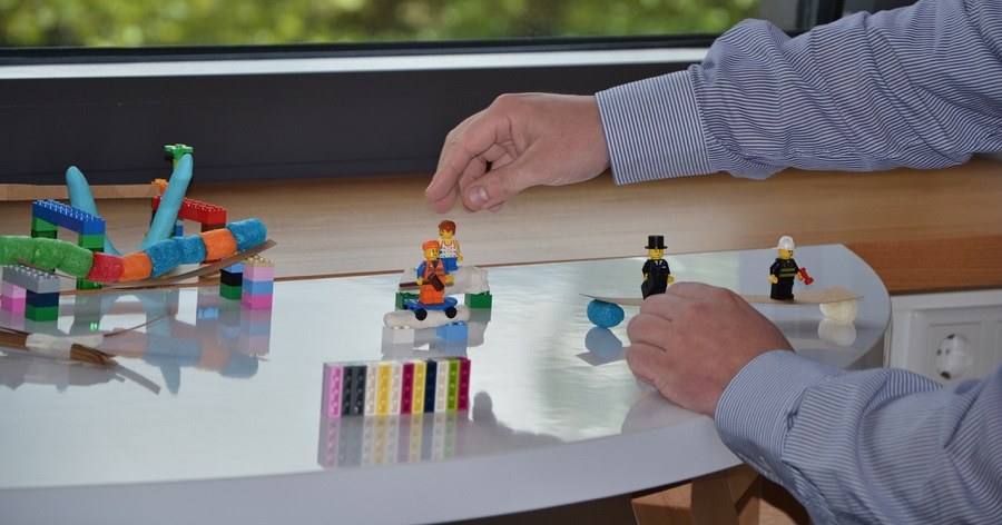 Lego-Bausteine Auf einem Tisch stehen Lego-Bausteine und -figuren, die zusammen gebaut werden.