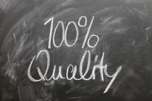 Bild von einer Tafel, auf der mit Kreide geschrieben "100 % Quality" steht.