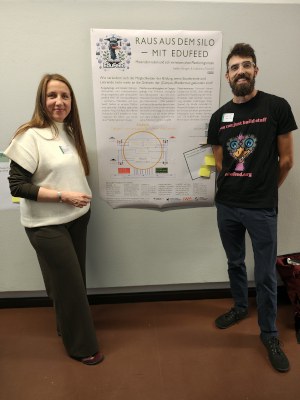 Zwei Personen posieren vor einem Poster